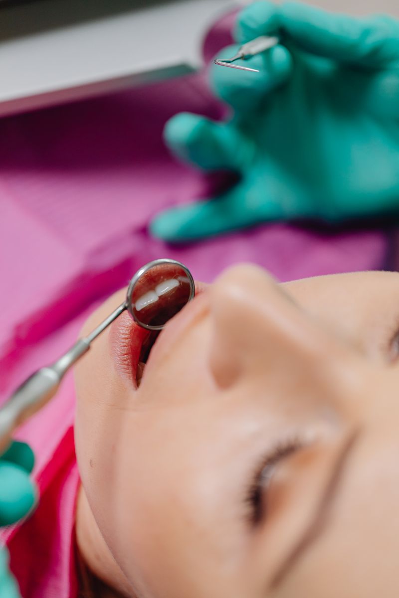 A dentist's steady, gloved hands at work during a dental examination.